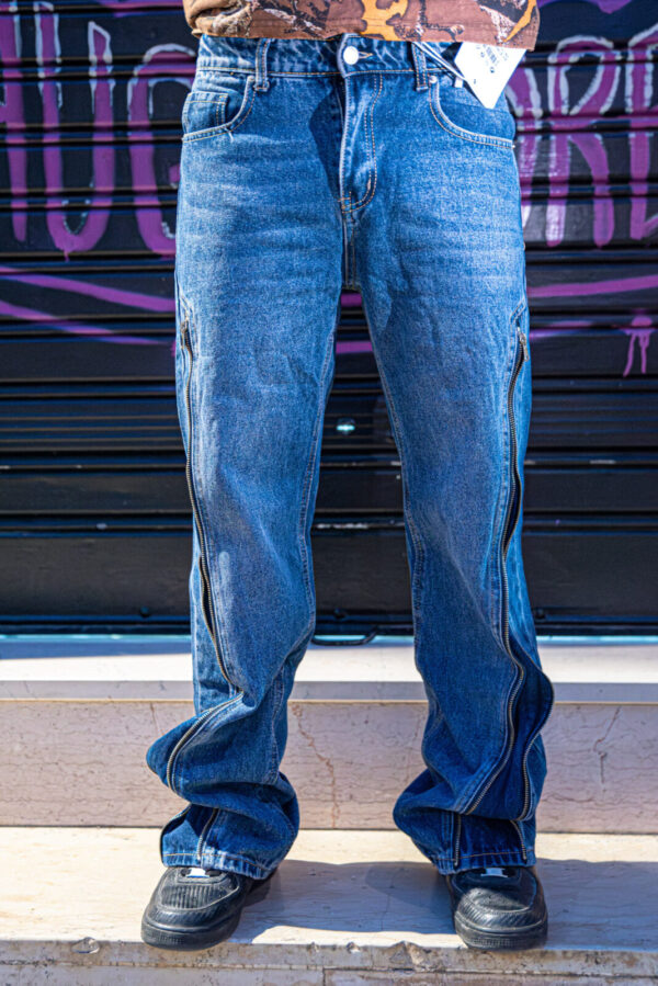 Jeans straight fit con zip laterali visibili, indossati con scarpe nere e sfondo urbano.